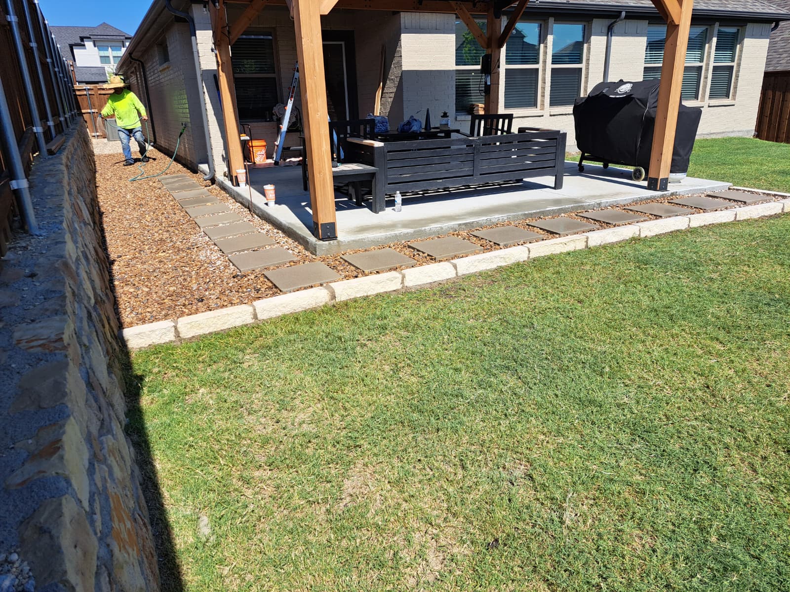 Backyard landscaping with stone border and lawn improvement in Burleson, TX